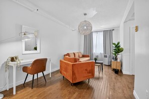 A modern living room with a sofa, a chair, a small table, and a hanging light fixture. - Capital Region 1BR | Minutes to Attractions (Gatineau)
