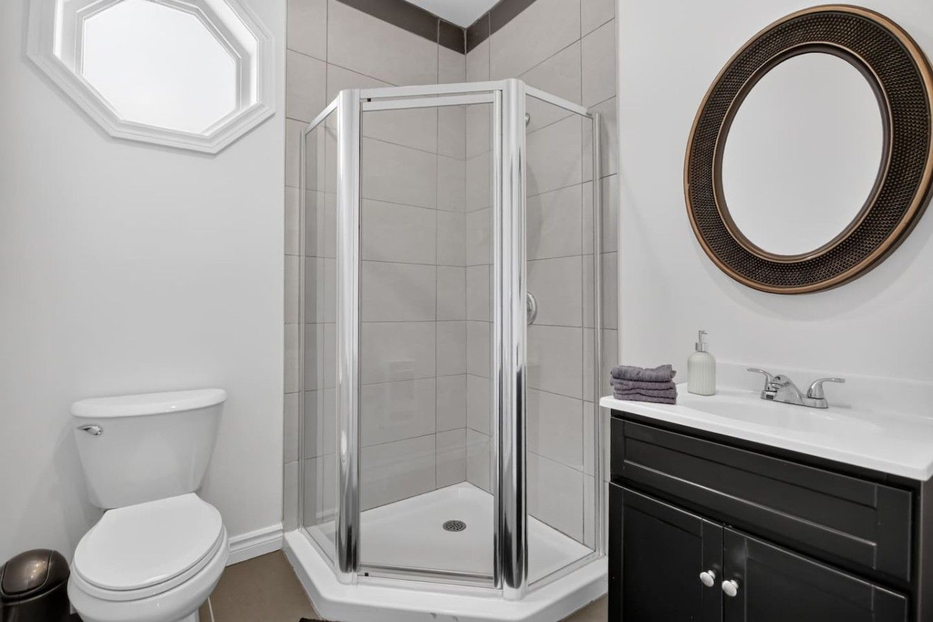 Une salle de bain avec une douche à parois de verre, des toilettes, un lavabo avec un miroir et une serviette posée sur le comptoir.