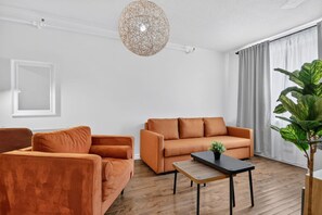 A modern living room with a sofa, armchair, and a coffee table. - Capital Region 1BR | Minutes to Attractions (Gatineau)
