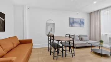 Un salon moderne comprenant un canapé, une table à manger avec des chaises, une table basse, un miroir et un tableau accroché au mur.