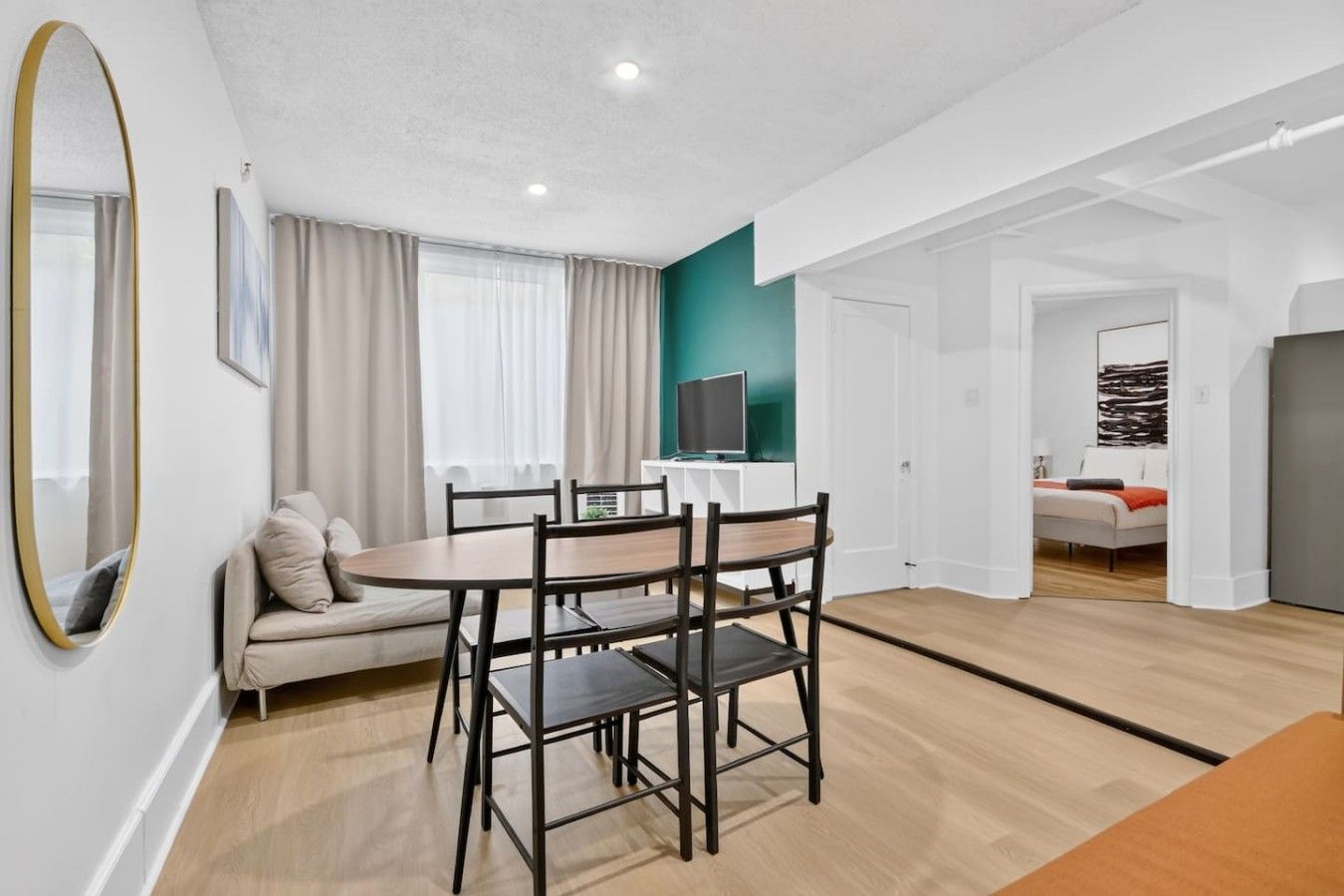 Un salon moderne comprenant un coin repas, un canapé, un téléviseur et une chambre à coucher dans la pièce adjacente.