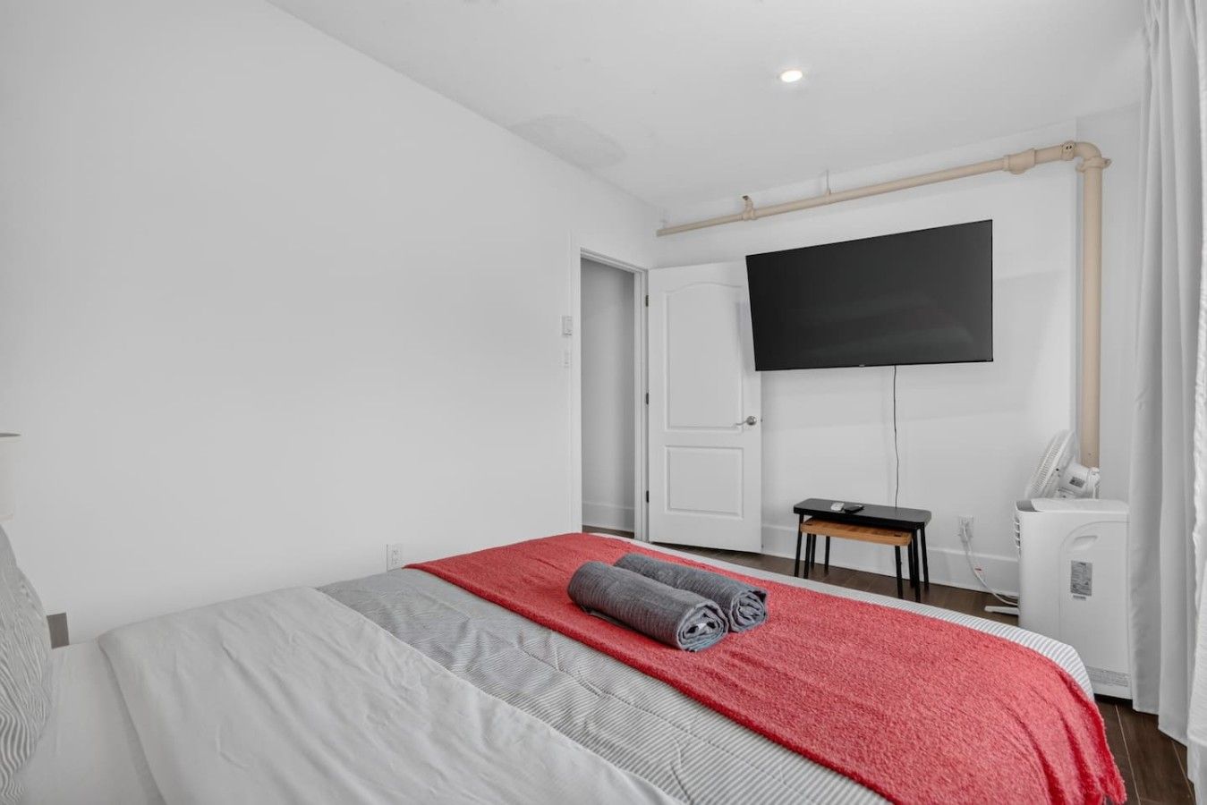 Een hotelkamer met een bed, een aan de muur bevestigde televisie, een bureau en een stoel.
