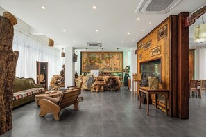A spacious room with a large wooden sculpture, a sofa, and a dining table. - Chennianwangshiyisu (Guilin)