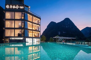 Un hotel con piscina y montañas al fondo.