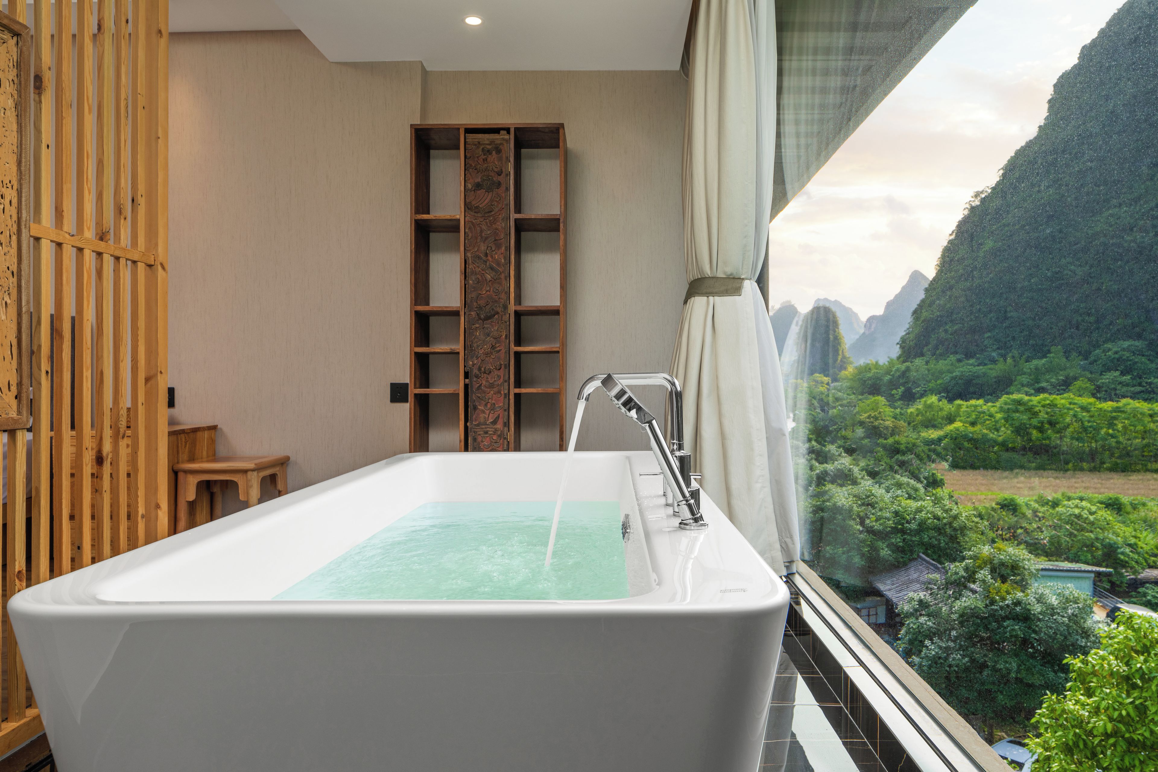 A modern bathroom with a freestanding bathtub, wooden paneling, and a view of a mountainous landscape.