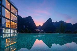 A modern hotel with a pool reflecting the mountains and sky. - Chennianwangshiyisu (Guilin)