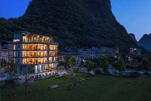 A multi-story hotel with a modern design, situated in a mountainous area with a view of the surrounding landscape. - Chennianwangshiyisu (Guilin)