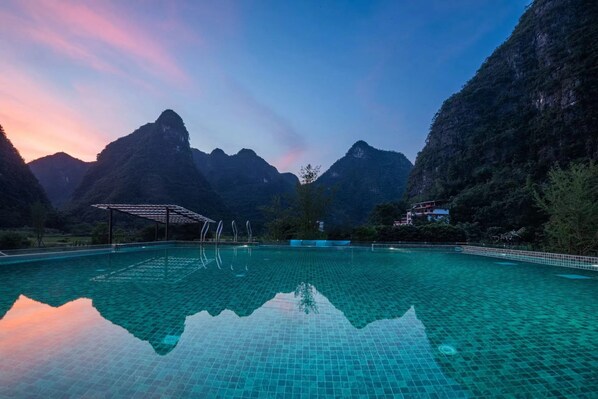 A swimming pool with clear water reflecting the surrounding mountains.