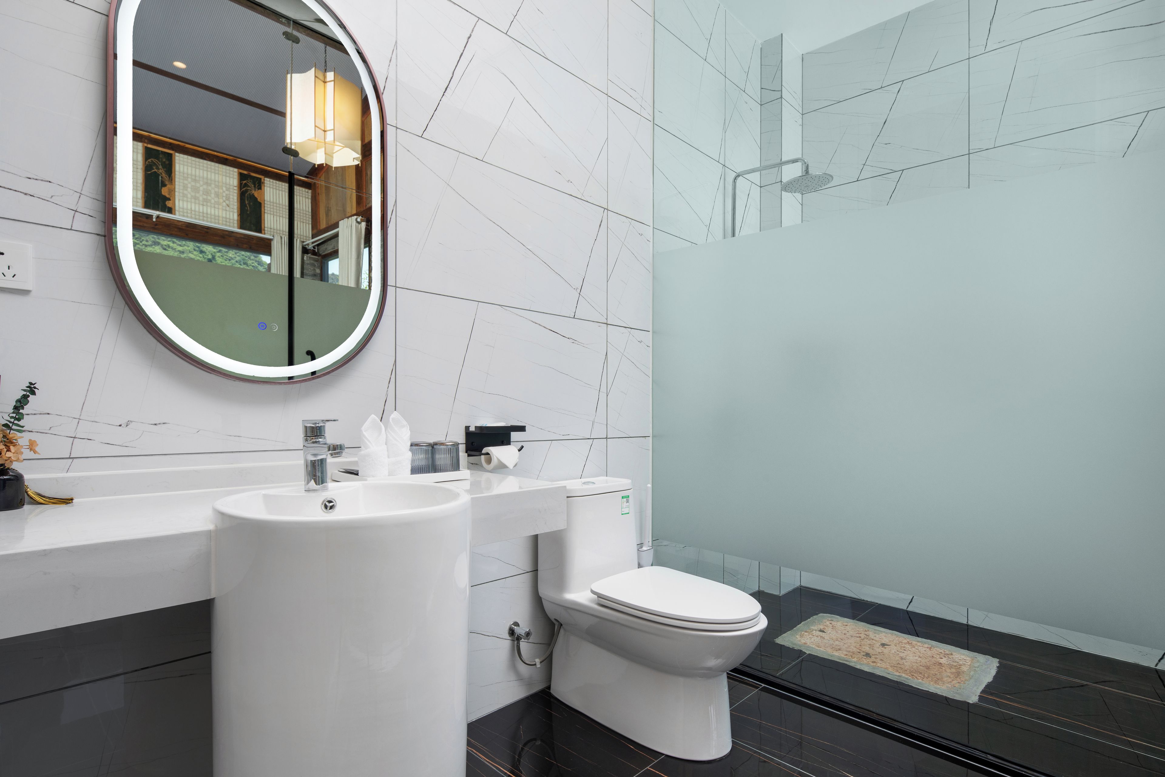 Un baño moderno con un espejo redondo, un lavabo, un inodoro y una zona de ducha.