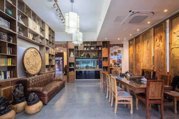 A spacious room with a leather sofa, wooden shelves, and a dining area with chairs. - Chennianwangshiyisu (Guilin)