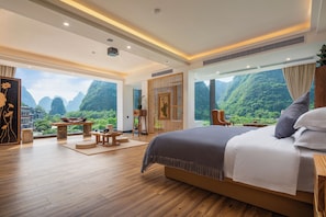 Un dormitorio amplio con una cama grande, piso de madera y vista a la vegetación exuberante.