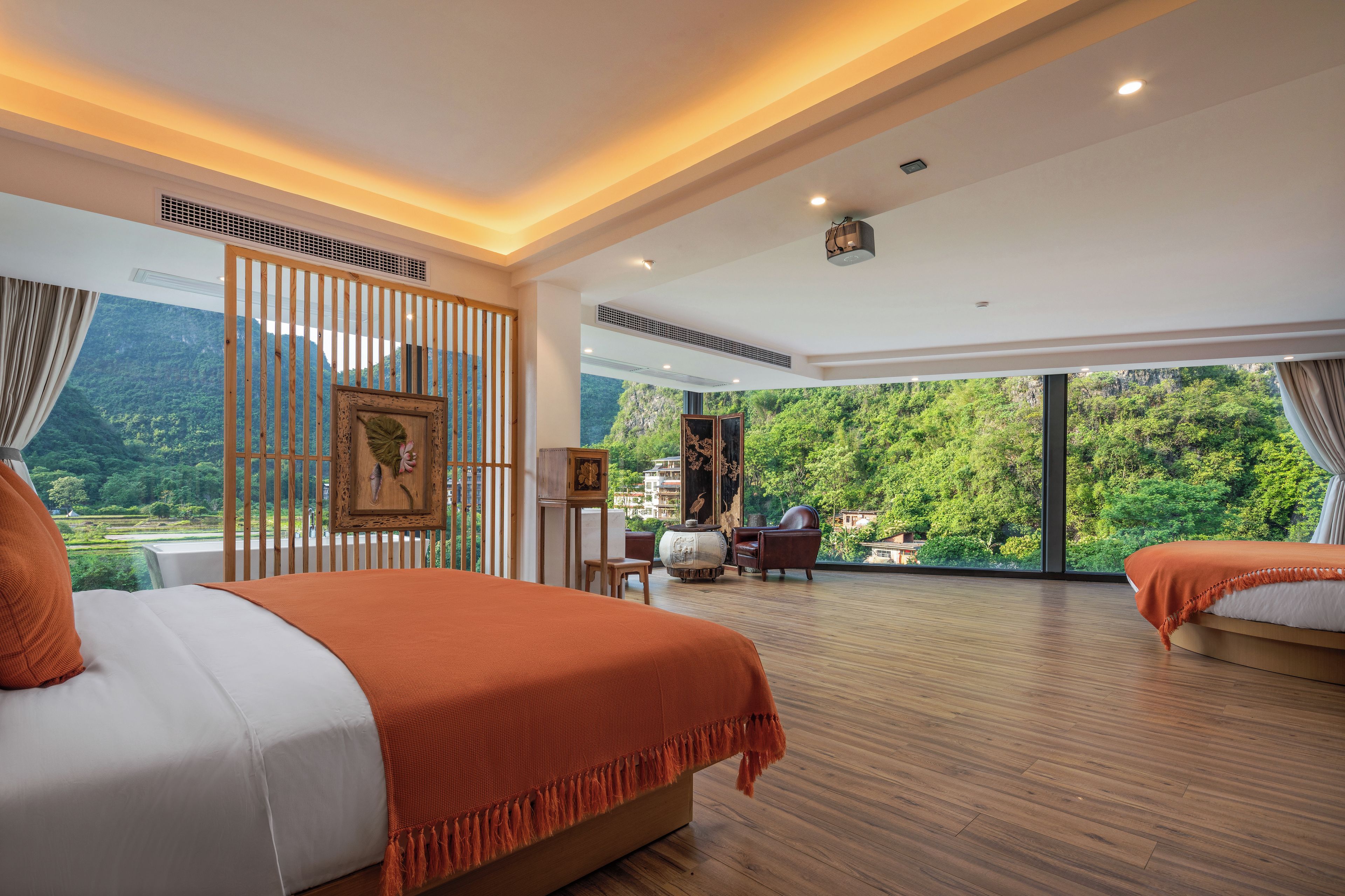 A spacious bedroom with a large bed, a seating area, and a view of a lush forest.