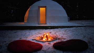 Paisaje nevado con una estructura en forma de cúpula blanca y una entrada iluminada.