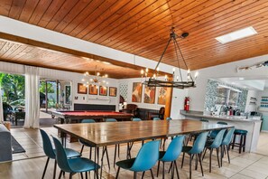 Un grand espace intérieur comprenant une table de billard, des chaises de salle à manger et un coin cuisine avec un mur recouvert de carreaux.