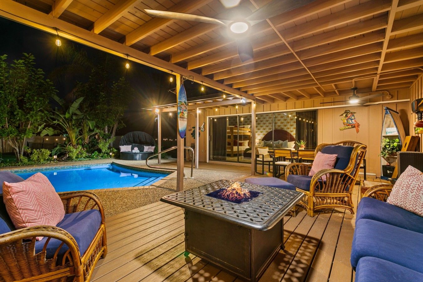 An outdoor patio with a pool, seating area, and a fire feature.