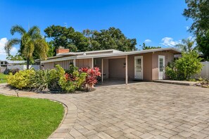 A single-story house with a covered porch, a brick driveway, and a well-maintained lawn. - Bayou Breeze| PickleBall, Pool, Sports Court | AMI (Bradenton)