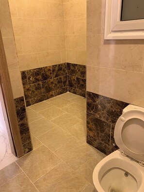 Ein Badezimmer mit Toilette, einer Duschkabine und Fliesenboden.