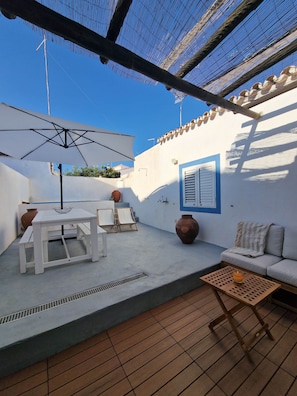 A patio with a white table, two chairs, a wooden coffee table, a white umbrella, and a sofa. - Casa de Santa Margarida (Mourão)