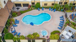 Ein Schwimmbecken, umgeben von Liegestühlen und einer kleinen Whirlpool-Badewanne.