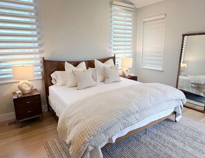 A bedroom with a large bed, two bedside tables, a nightstand, a bedside lamp, a rug, and a mirror. - Balsam Preserve Private Resort | Golf, Spa, Hiking (Sylva)