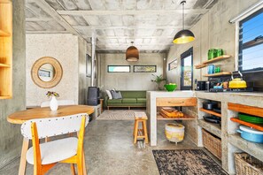 A compact living space with a kitchenette, a dining area, and a sofa. - KOH Pringle Pod - One Bedroom House, Sleeps 2 (Pringle Bay)