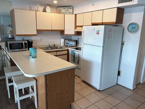 A kitchen with a central island, a microwave, a toaster, a sink, and a refrigerator. - Inviting beach condo with pool access and easy Ocean City fun (Ocean City)