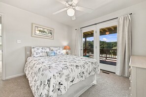 A bedroom with a bed, a ceiling fan, a framed picture, and a view through a glass door. - Walk to Beach in Duck·Hot Tub·Sound Access·Dogs OK (Kitty Hawk)