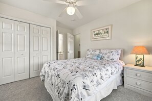 A bedroom with a bed, a nightstand, a lamp, a ceiling fan, and a door. - Walk to Beach in Duck·Hot Tub·Sound Access·Dogs OK (Kitty Hawk)