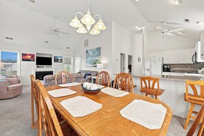 A modern kitchen with white cabinets, a dining area with a wooden table and chairs, and a ceiling fan. - Walk to Beach in Duck·Hot Tub·Sound Access·Dogs OK (Kitty Hawk)