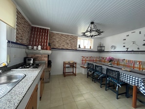 Une cuisine équipée d’une cuisinière à gaz, d’un évier et d’un coin repas avec une nappe à carreaux.