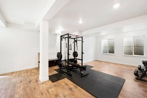 A spacious room with a weightlifting area, a bench, and a window with blinds. - Sundance 2027 Retreat //4BR + Gym + 2-Car Garage (Superior)