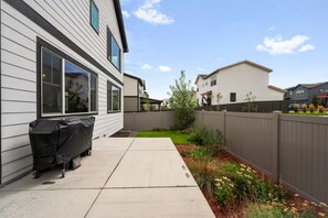 A residential backyard with a patio, a barbecue grill, a wooden fence, and a lawn with flowers. - Sundance 2027 Retreat //4BR + Gym + 2-Car Garage (Superior)