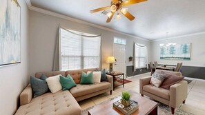 A living room with a beige sectional sofa, a coffee table, and a dining area with a table and chairs. - University Place - 3.5 miles to Kyle Field, Pool access! (College Station)