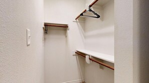 A narrow hallway with white walls, a wooden door frame, and a coat rack with a black hanger. - University Place - 3.5 miles to Kyle Field, Pool access! (College Station)
