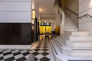 A hotel lobby with a checkered floor, a staircase, and a dining area with a view of the outside. - South Beach - Copacabana (Rio de Janeiro)