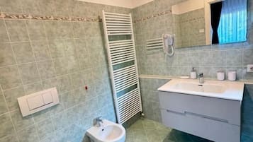 Un baño con inodoro, bidé, lavamanos y espejo.