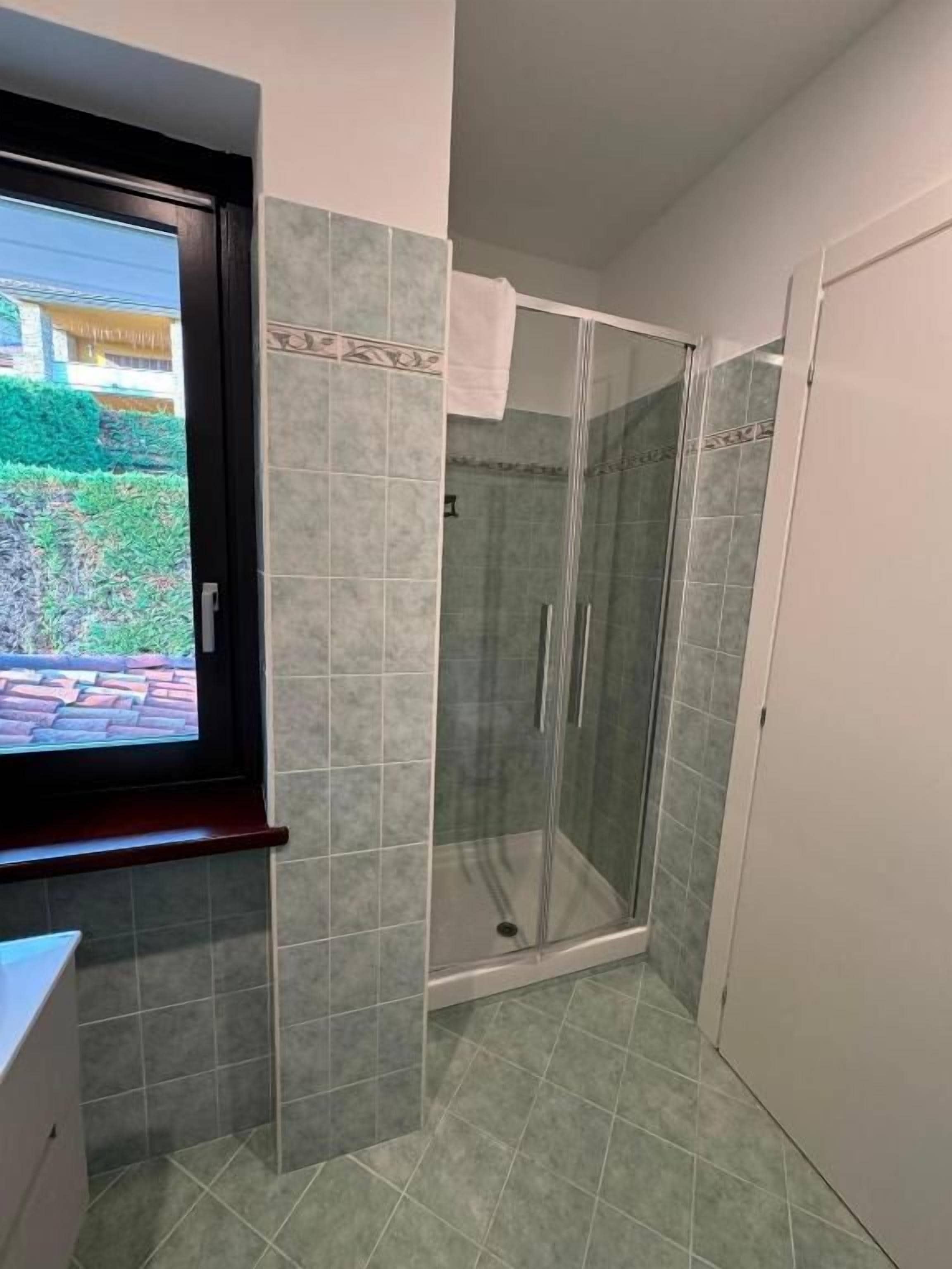 A bathroom with a glass shower enclosure, a window, and a door.