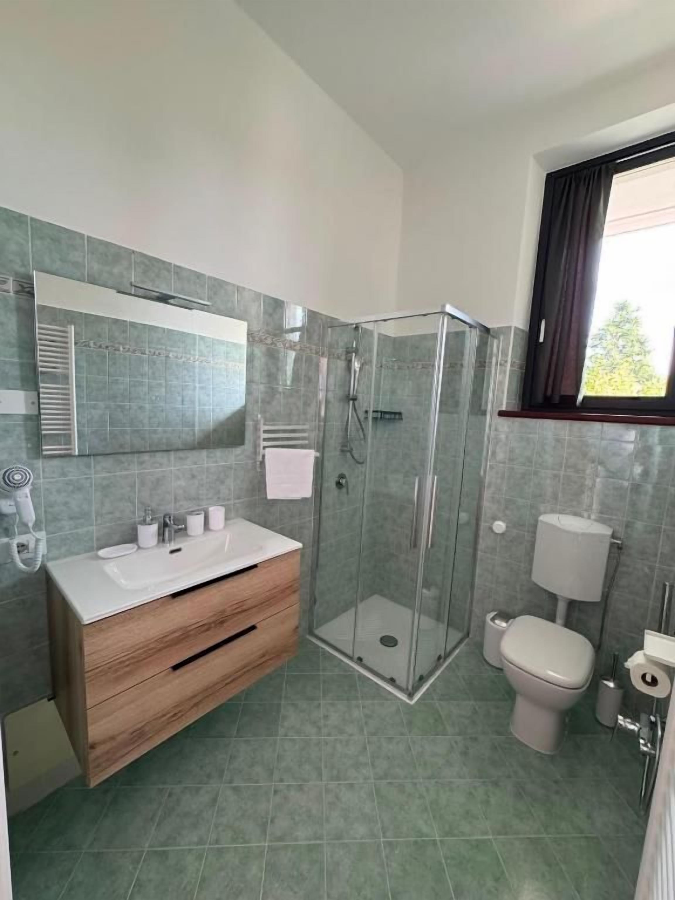 Une salle de bain moderne avec une douche à parois de verre, un meuble-lavabo en bois, des toilettes et un bidet.