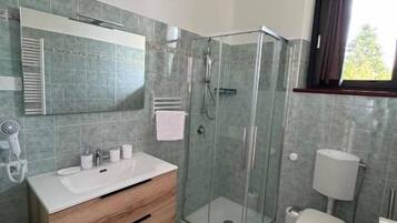 Une salle de bain moderne avec une douche à parois de verre, un meuble-lavabo en bois, des toilettes et un bidet.