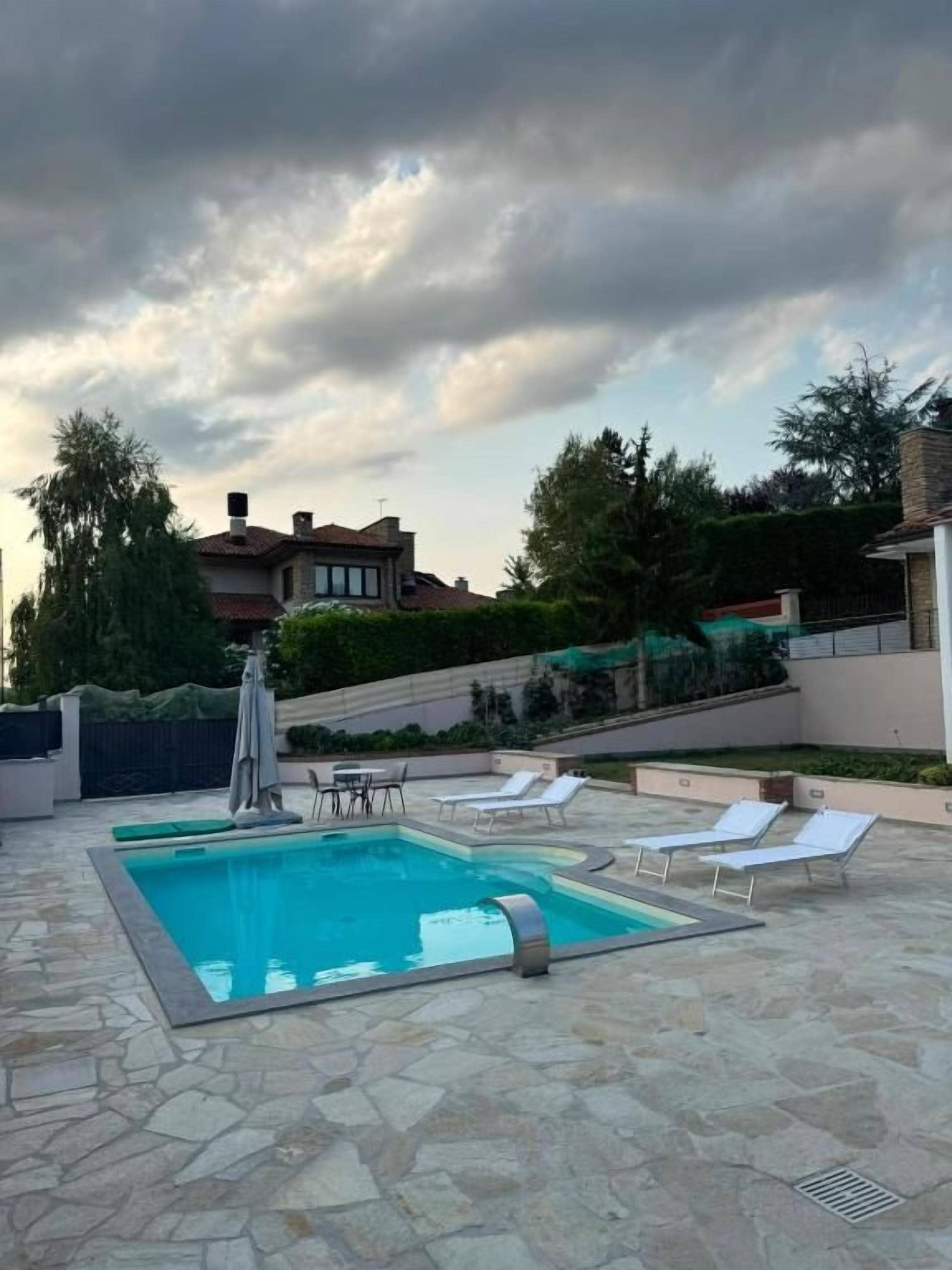 Ein Schwimmbecken mit Liegestühlen, einem Tisch und einer Pergola.