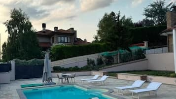 Ein Schwimmbecken mit Liegestühlen, einem Tisch und einer Pergola.