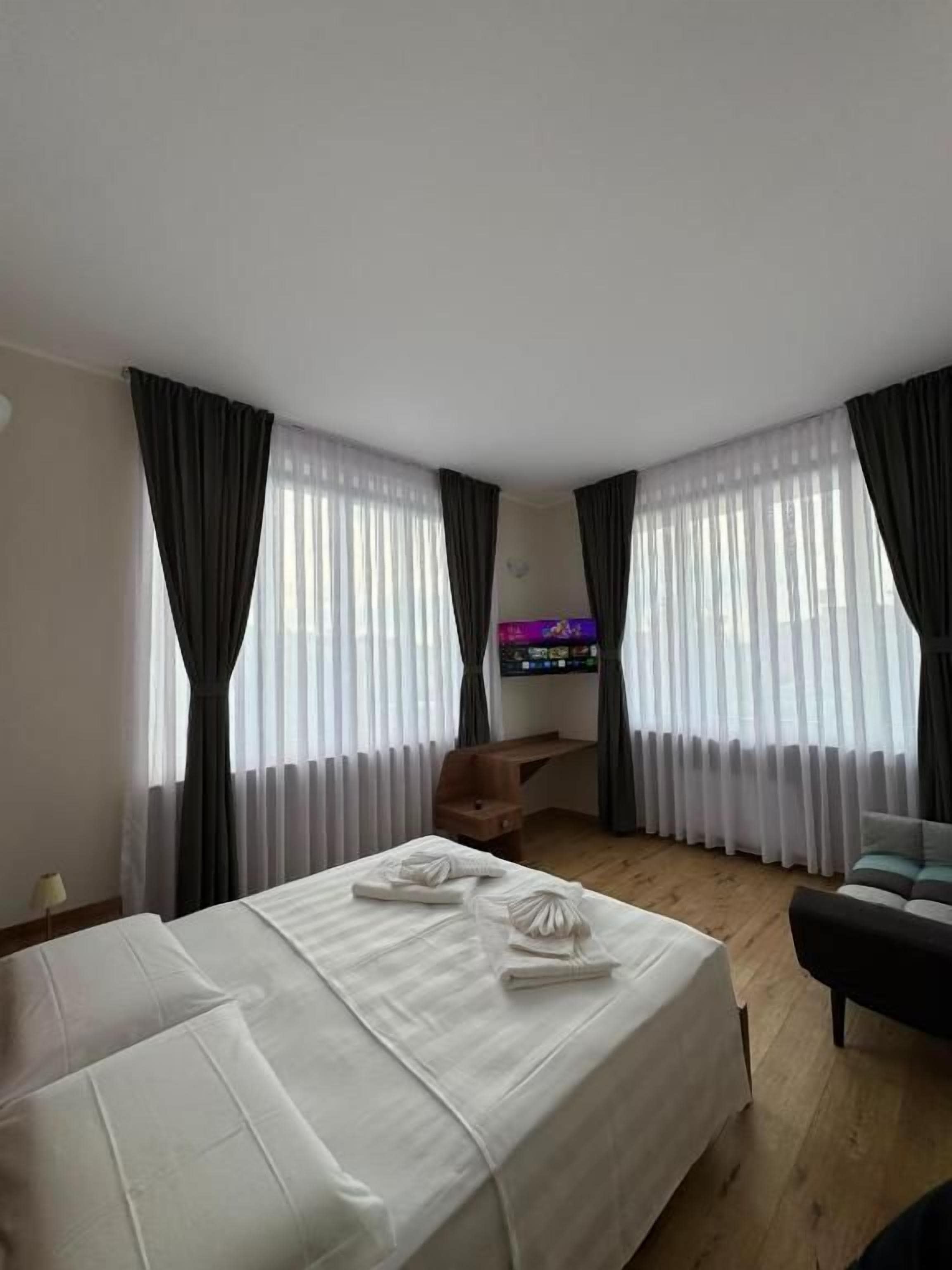 A hotel room with two beds, a desk, a chair, and a television.