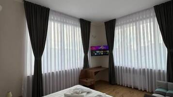 A hotel room with two beds, a desk, a chair, and a television.