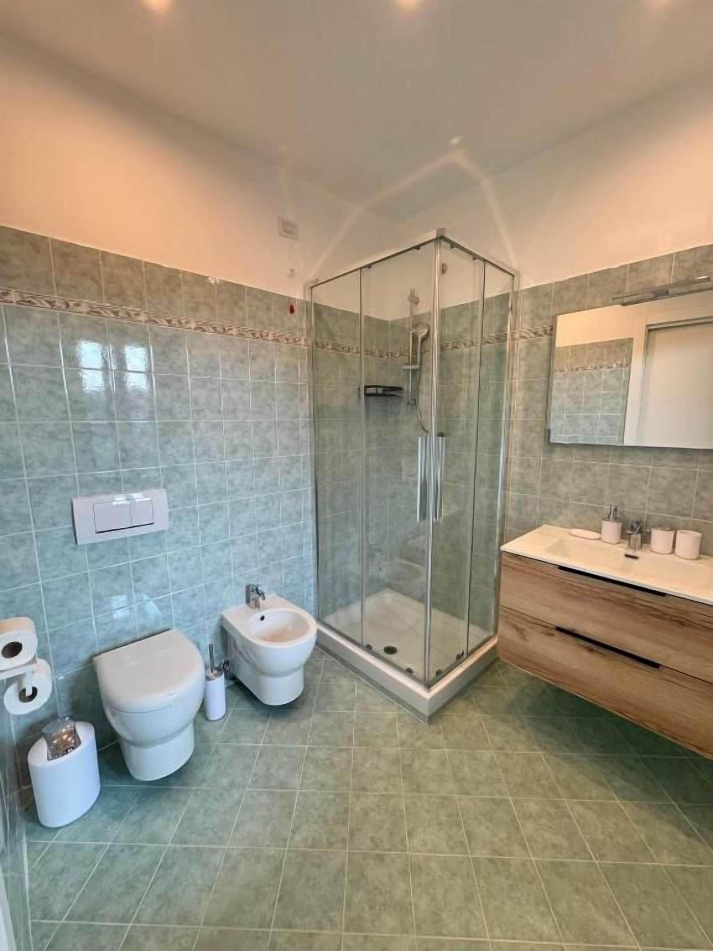 A modern bathroom with a glass-enclosed shower, a vanity with a mirror, and a toilet.