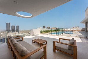 A rooftop terrace with a pool, seating area, and city views. - Stayshort - Elegant 1 Bedroom in JVC That Sleeps 2 (Dubai)