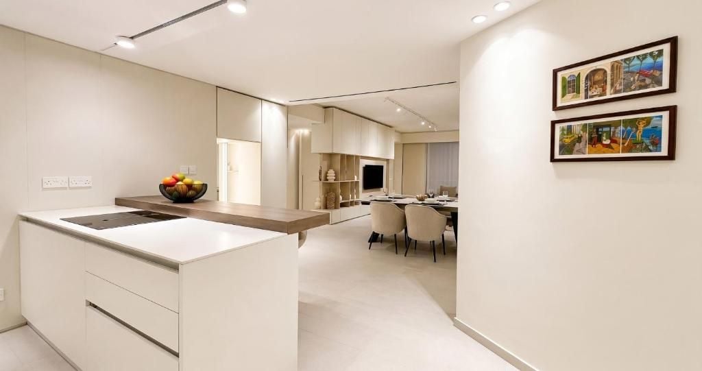 Una cocina moderna con una isla central, una zona de comedor con sillas y dos cuadros en la pared.