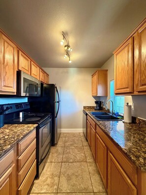 A kitchen with wooden cabinets, a stainless steel refrigerator, a microwave, a stove, and a granite countertop. - 7 Bell Rock Villas Condo W/Red Rock View + Hot Tub (Sedona)