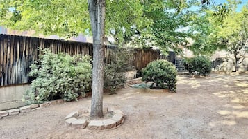 A garden with a tree, shrubs, and a wooden fence.