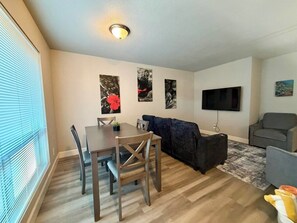 A living room with a dining table, a dark sofa, a grey armchair, and a flat-screen TV mounted on the wall. - 7 Bell Rock Villas Condo W/Red Rock View + Hot Tub (Sedona)
