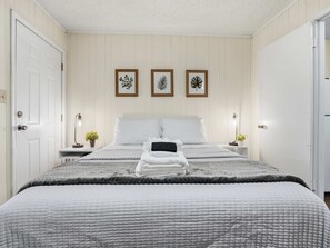 A neatly arranged bedroom with a bed, bedside tables, and framed artwork on the wall. - 4 Min Downtown - 7 Min to Duke - 9 Min to Hospital (Durham)